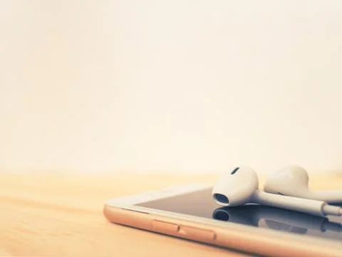 Earbuds on top of smartphone and reflection Stock Photos