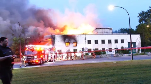 Early arrival at major structure fire with flames and firefighters Stock Footage 115981719