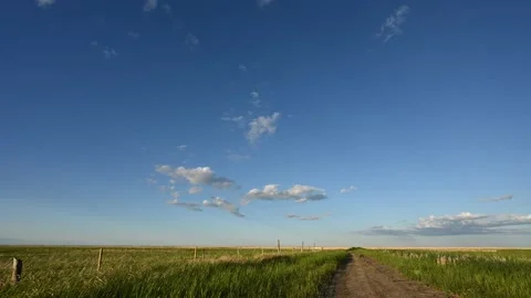 Early evening clouds drift through a blue sky in this time lapse over a prairie  Stock Footage 156298618