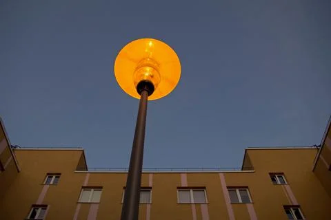 Early lighted rounded lantern on black holder on background of top of building. Stock Photos