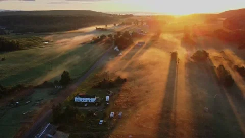 Early in the morning, drones fly over farmhouses, fields and pastures as the gol Stock Footage 170938867