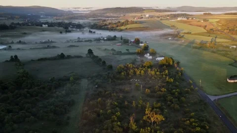 Early in the morning, drones fly over farmhouses, fields and pastures as the gol Stock Footage 170938892