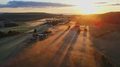 Early in the morning, drones fly over farmhouses, fields and pastures as the gol Stock Footage 170938895