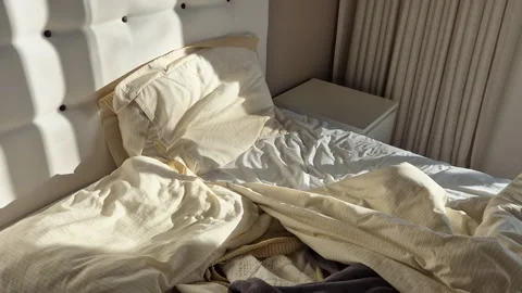 Early morning sunlight casting long shadows across an unmade bed Stock Footage 331019864