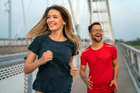 Early morning workout. Happy couple running across the bridge. Living healthy Stock Photos