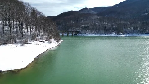 Early Spring Mountain Lake During Snow Thaw With Forest And Bridge Stock Footage 330240633