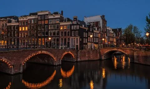 Early spring night view of amsterdam cityscape with canal bridge and medieval Stock Photos