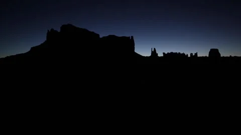 Early twilight light silhouetting rocky buttes and spires in Monument Valley Stock Footage 253247151