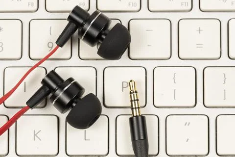 Earphone with red cord on computer white keyboard closeup Stock-Fotos