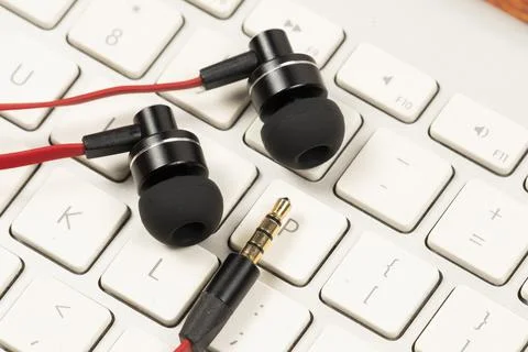 Earphone with red cord on computer white keyboard closeup Foto stock