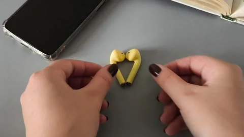 Earphones lie on a table in the shape of a heart and female hands take them from Stock Footage 320447780