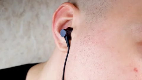 Earpiece in your ear. Wired earpiece in a man's ear. A man listening earpiece Video stock 281208946