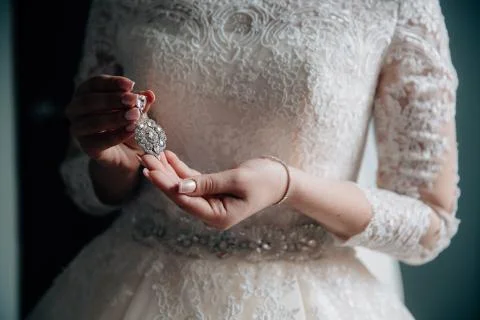 Earrind in the hands of the bride on black background. Concept of jewelry Stock Photos