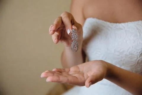 Earrind in the hands of the bride Stock Photos