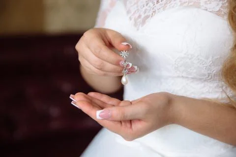 Earrind in the hands of the bride Stock Photos