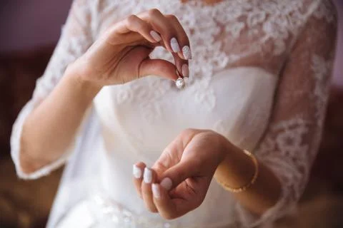 Earrind in the hands of the bride Stock Photos