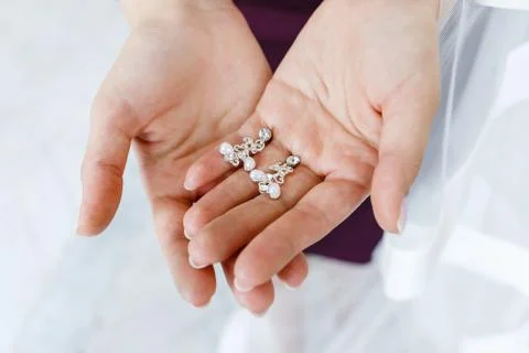Earrings in the hands of the bride. Stock Photos