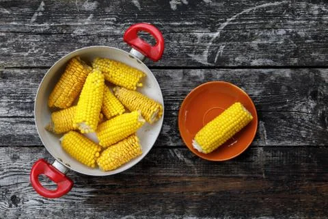 Ears of corn boiled. corn in a saucepan on a wooden background. top view, flat Stock Photos