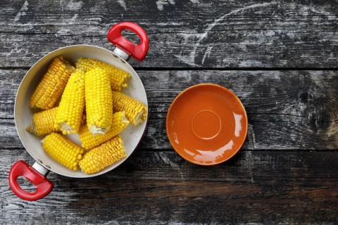 Ears of corn boiled. corn in a saucepan on a wooden background. top view, flat Stock Photos