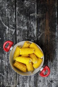 Ears of corn boiled. corn in a saucepan on a wooden background. top view, flat Stock Photos