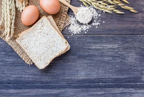 Ears of wheat and egg with slice of bread on a wooden table Stock Photos