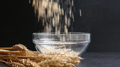 Ears of wheat and muesli falling into empty transparent glass bowl,slow motion Stock Footage 97710286