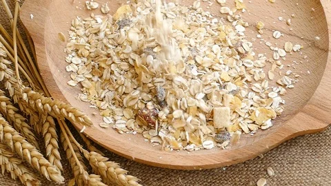Ears of wheat and muesli falling into empty wooden plate,slow motion Stock Footage 97710717