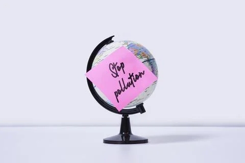 The Earth globe with a sticker and note - stop pollution Stock Photos