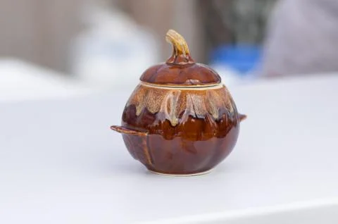 Earthenware pot made in shape of pumpkin standing on a light surface Foto stock