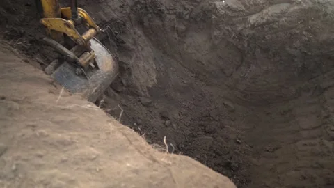 An earthmoving machine digs a hole at a construction site in winter Stock Footage 148635036