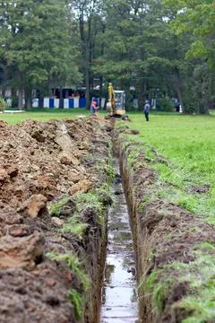 Earthwork construction work using a mini excavator technique. Trench for laying Stock Photos