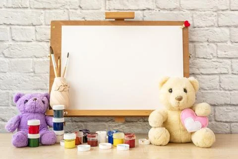 Easel mockup with white blank, stuffed toy Teddy bear and brushes. Stock Photos