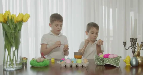 Easter atmosphere. two brothers draw eggs with a brush. Stock Footage 172523612