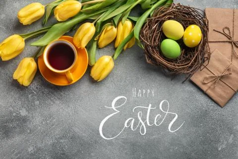 Easter background with blue, green eggs and a cup of tea in nest and yellow t Stock Photos