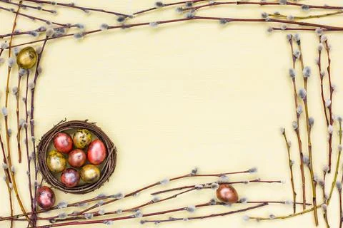 Easter background. Border of willow branch and quail eggs in small nest on Stock Photos