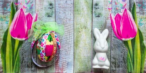 Easter background with bunny, egg and pink tulips on wooden texture. Banner Foto stock