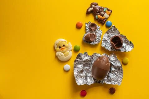 Easter background from chocolate Easter eggs and colorful candies on a yellow Foto stock