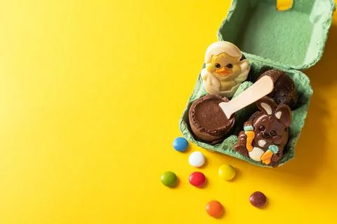 Easter background from chocolate Easter eggs and colorful candies on a yellow Stock Photos