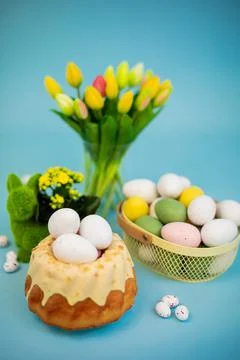 Easter background with colored eggs, easter cake, spring flowers on a blue Stock Photos