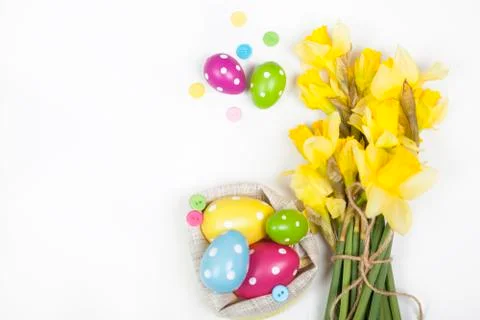 Easter background with colorful Easter eggs and a bouquet of yellow daffodils Stock Photos