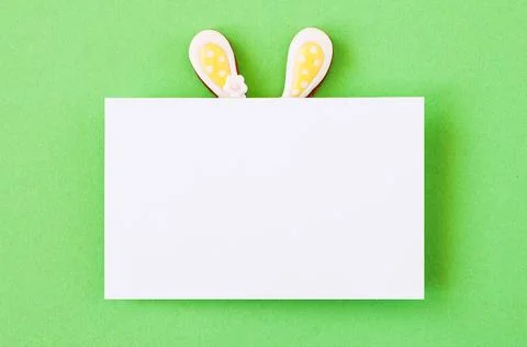 Easter background concept. Easter bunny ears under white empty paper on green Stock Photos