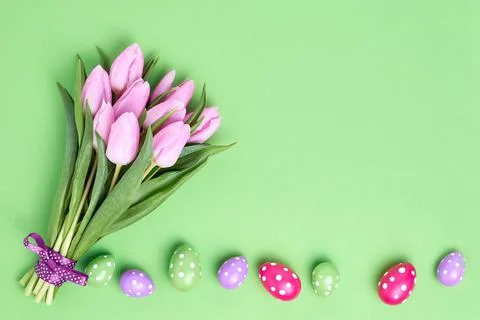 Easter background. Decorative Easter eggs and pink tulips bouquet on green Foto stock
