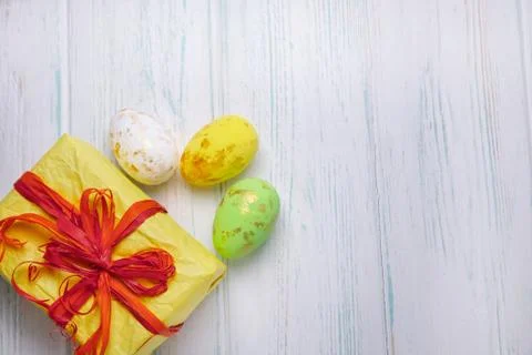 Easter background. Easter multi-colored eggs, gift box on a light wooden back Stock Photos