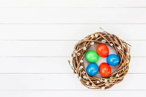 Easter background. Easter willow wreath, colorful Easter eggs on white wooden Stock Photos