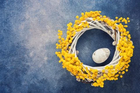 Easter background. Easter wreath with decorative egg on blue backdrop. Flat lay Stock Photos