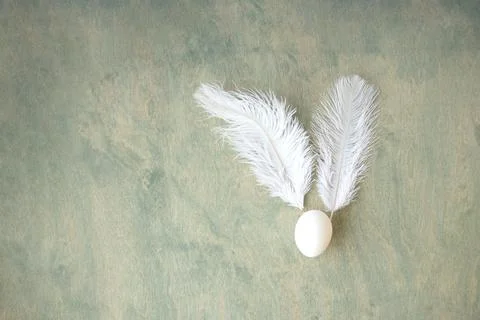 Easter background, egg and white feathers in form of hare on green wooden b.. Stock Photos