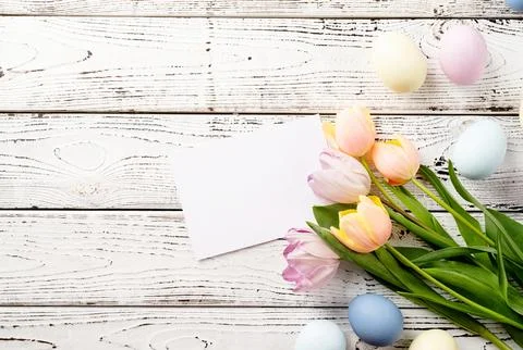 Easter background with eggs and tulips on white wooden backdrop, top view f.. Stock Photos