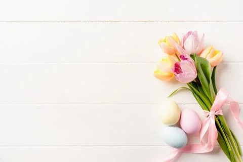 Easter background with eggs and tulips on white wooden backdrop, top view f.. Stock Photos