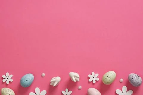 Easter background with eggs, bunnies and wooden flowers on pink background. P Stock Photos