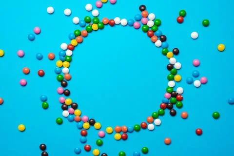 Easter background with multi-colored candy lie on a blue background. -Circl.. Stock Photos